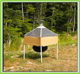 Picture of a horse fly trap. It contains a small tent shaped structure beneath which hangs a black ball shaped object.