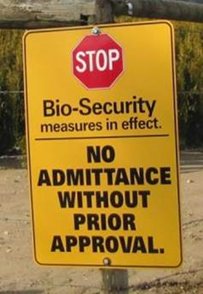 A biosecurity sign on a post in a field. Description follows.