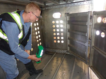 Un employé d'une station de lavage porte une combinaison et des chaussures propres pour inspecter une unité de transport.