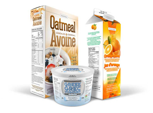 A 500 grams container of Greek yogourt at the front with a box of oatmeal cereal to the left and a 1.25 litre carton of orange juice to the right.