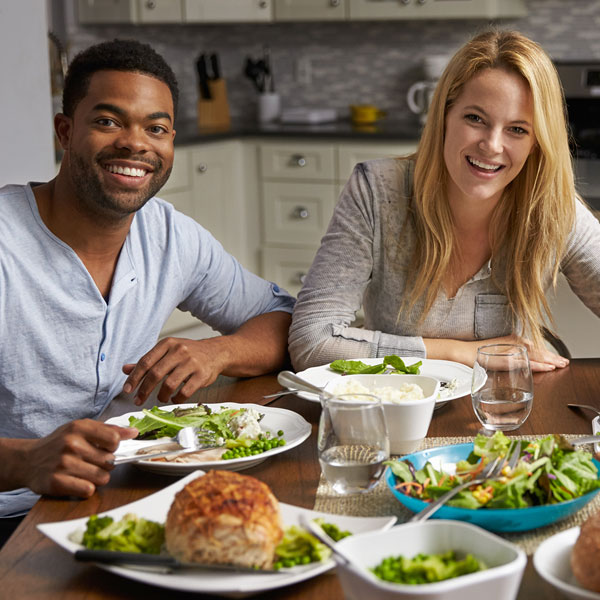 A family of three is eating dinner at their kitchen table.